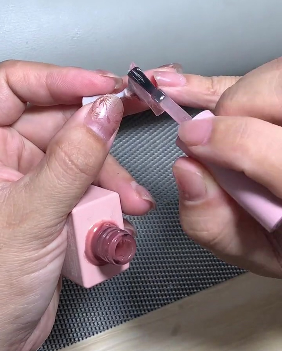 A nail with glitter gradient placed inside a UV lamp for curing.