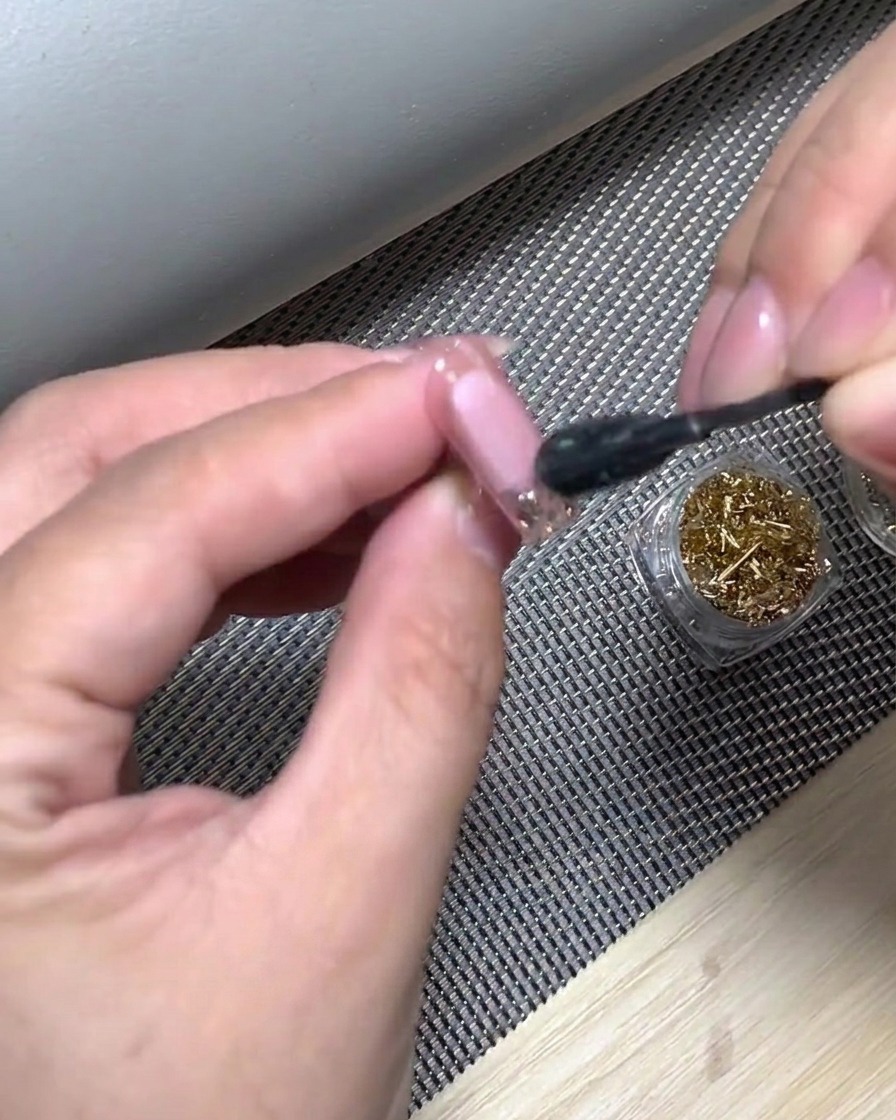 A hand positioned inside a UV nail lamp to cure the freshly applied white gradient tip.