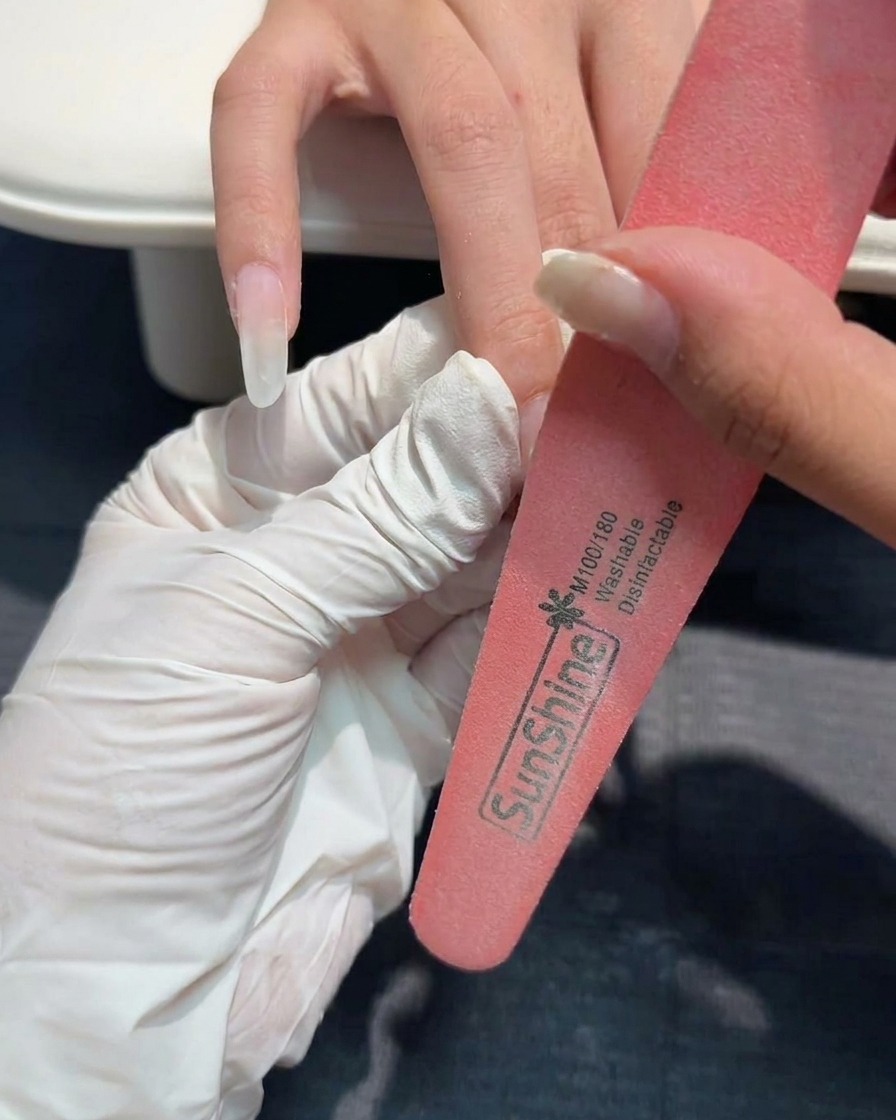 A hand-held nail file refining the surface of a structured gel nail.