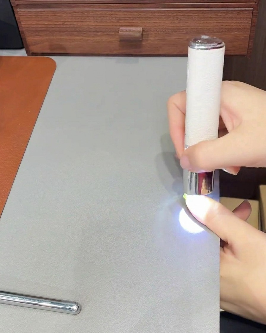 A hand holding a lint-free wipe, cleaning the surface of a nail that has just been cured.
