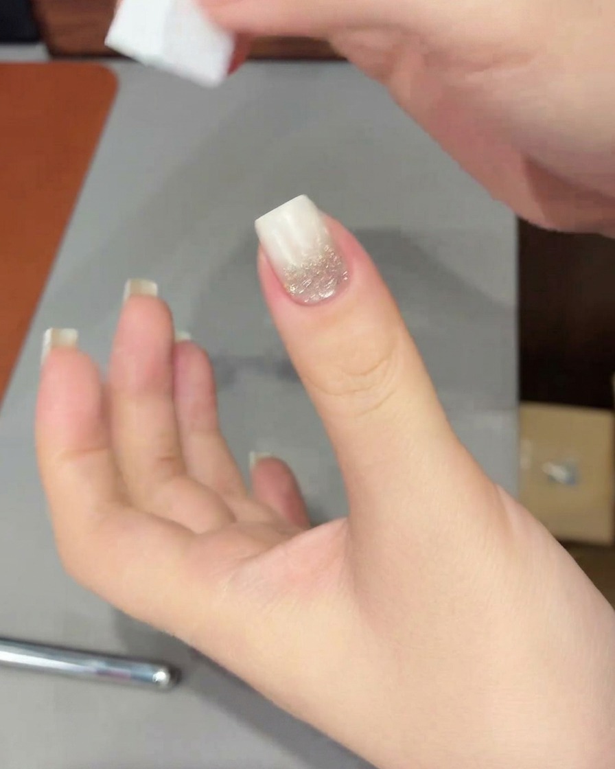 A hand with a white gradient tip placed inside a UV/LED lamp to cure the freshly applied gel.