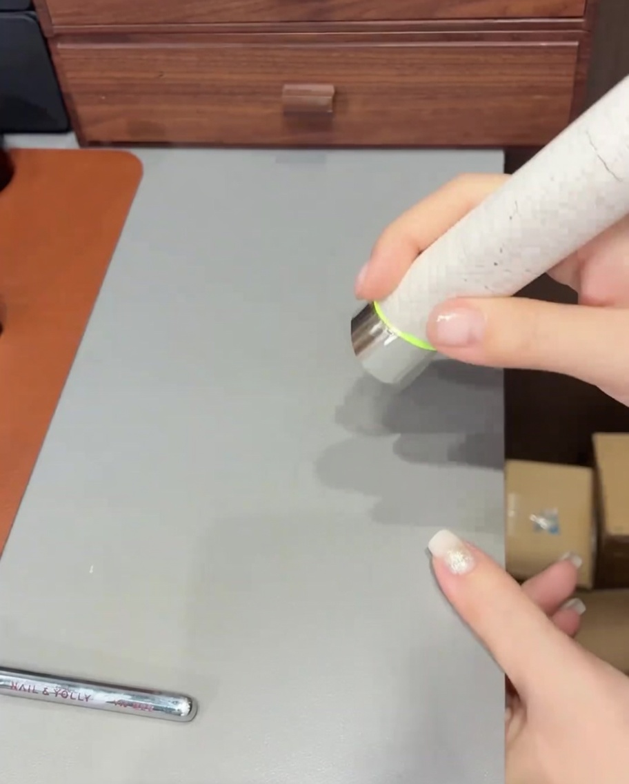 A brush applying a final layer of clear top coat over a glitter and ombre finished nail.
