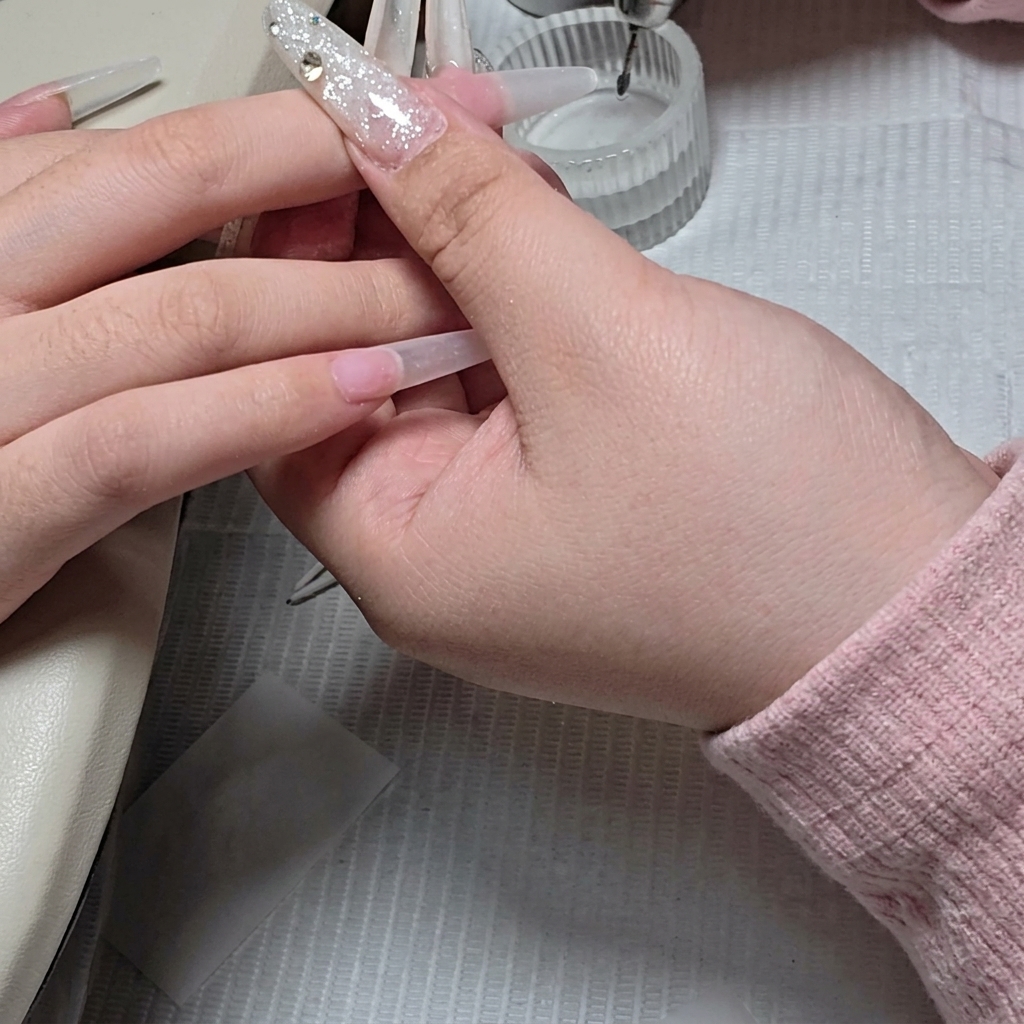 A close-up showing a small ball e-file bit being used for precise cleaning of the cuticle area.