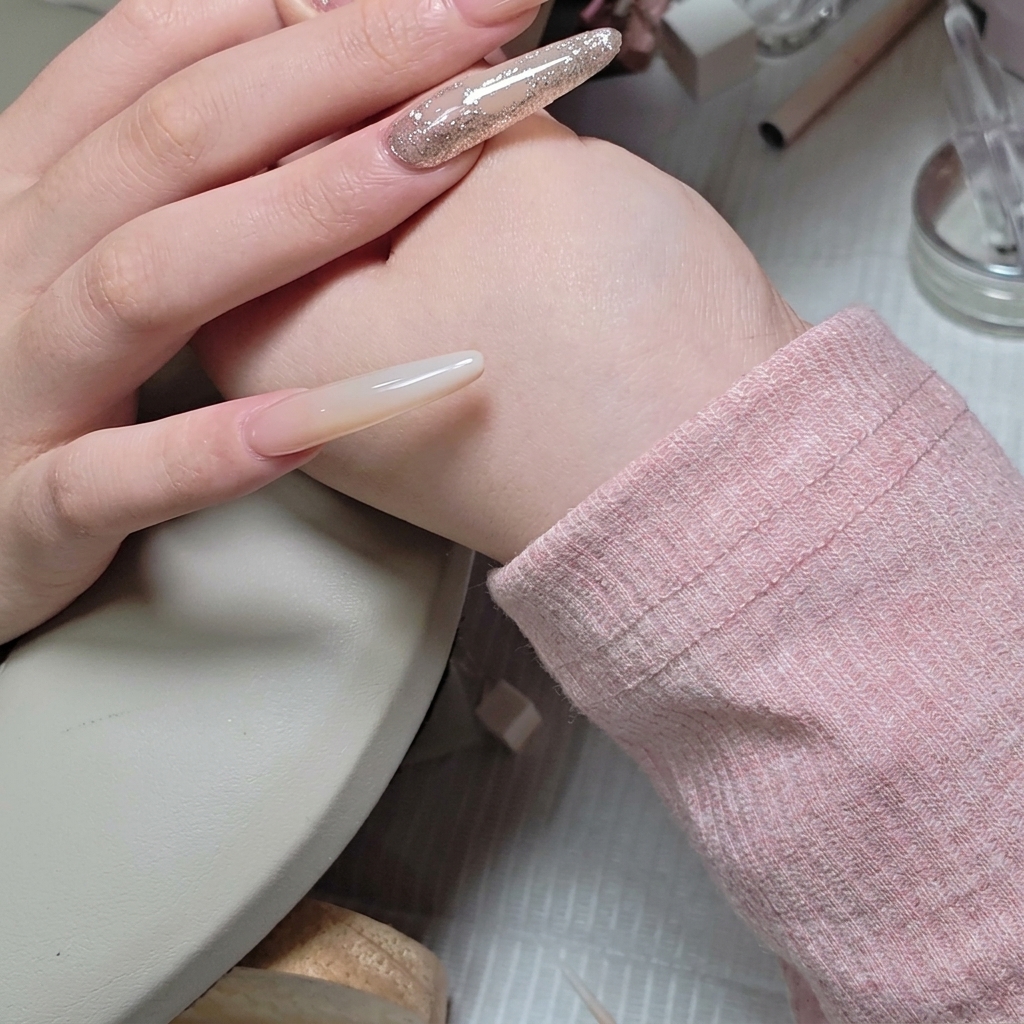 A fine-liner brush carefully applying a layer of clear builder gel around the edges of a set of rhinestones.