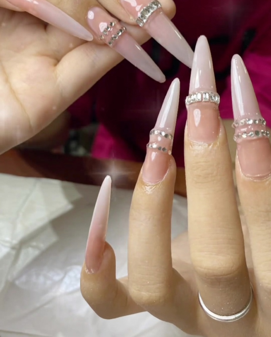 A brush applying glue to the underside of a clear, full-coverage nail tip.