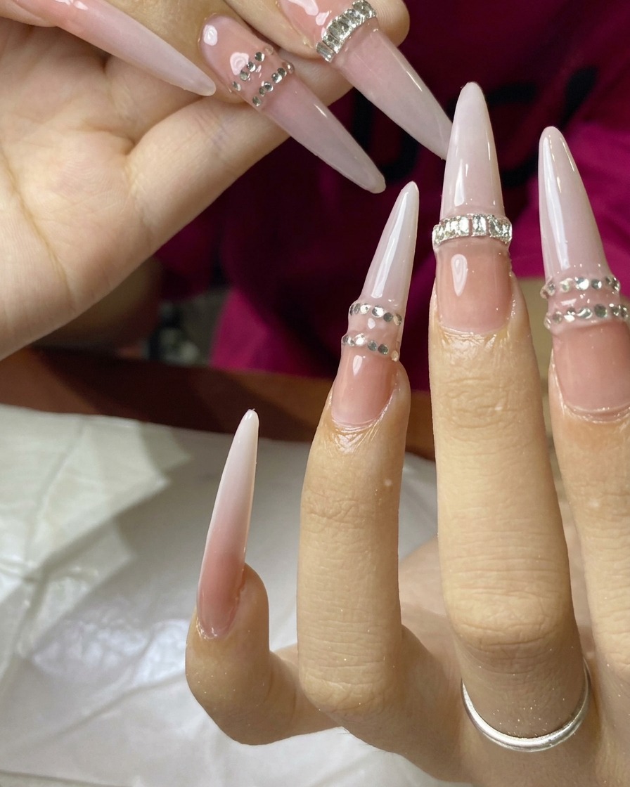 A close-up of a nail with a row of tiny rhinestones being applied and cured.