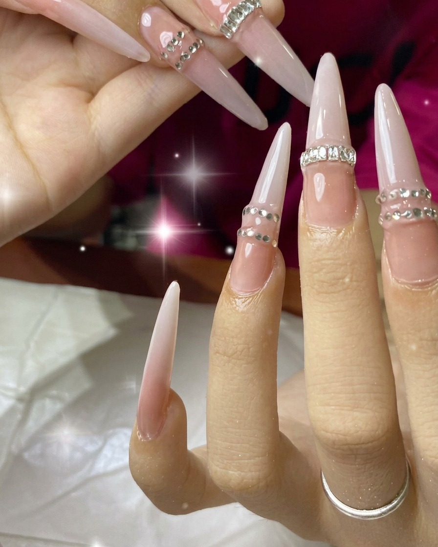A hand positioning a full-coverage press-on nail extension onto the ring finger.