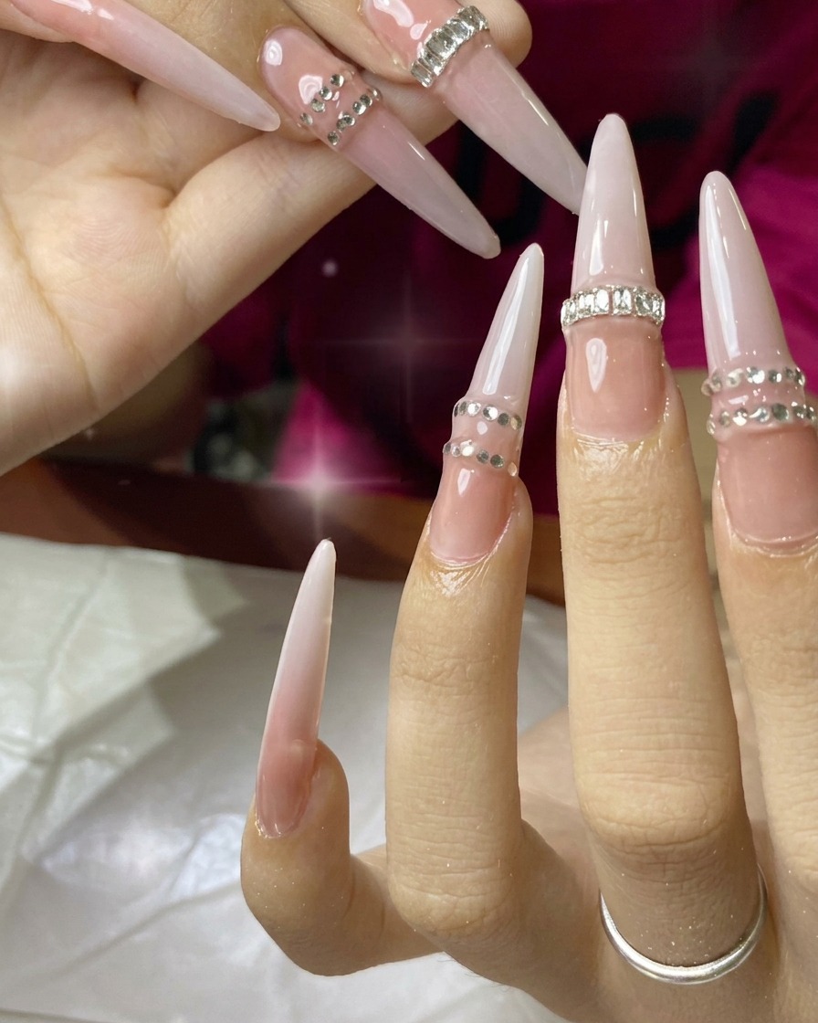 A nail brush applying a coat of nude gel polish to an extension nail.