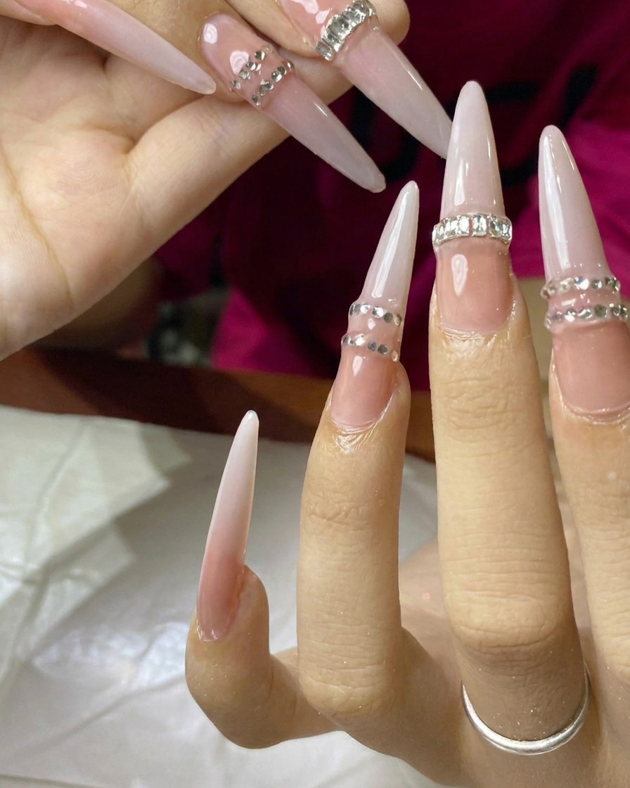 A brush blending milky white gel polish into the nude base on the nail surface.