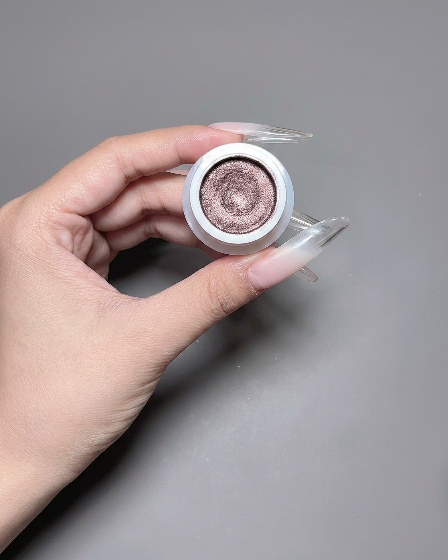 A brush applying a reflective, shimmery cat eye gel polish to a long nail.