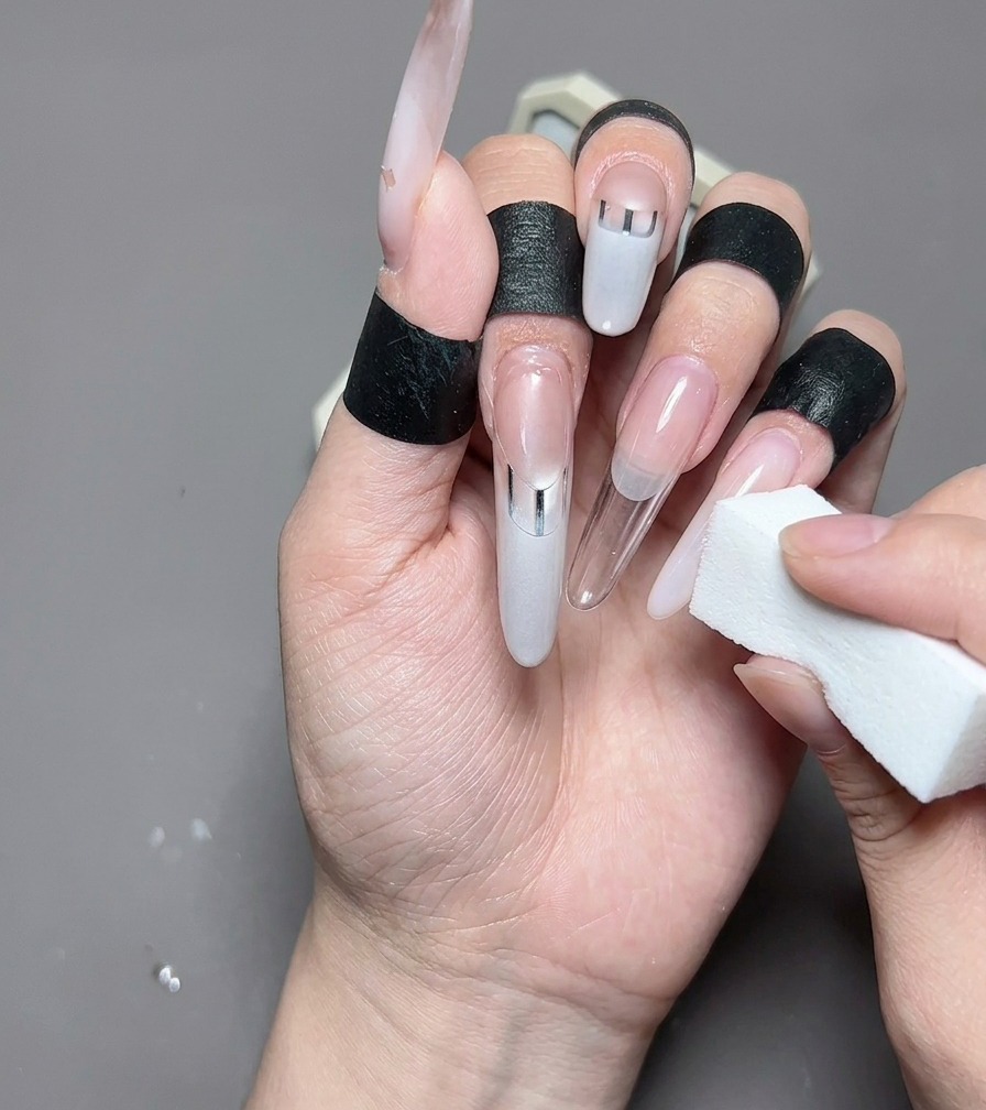 A close-up view of a liner brush painting a milky white French tip onto a clean, almond-shaped nail.