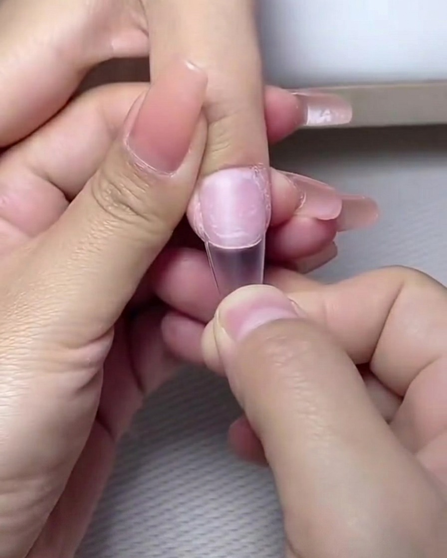 Fingers placed inside a professional UV/LED nail lamp for curing.