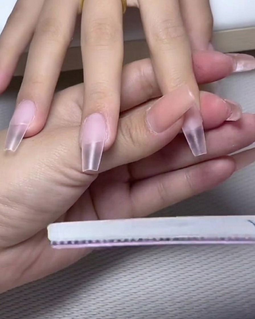 A nail brush applying a coat of opaque milk white gel polish to the top half of the nail.