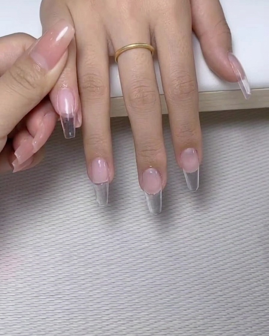 A fine-tip brush applying small dots of clear nail glue onto the surface of a manicured nail.