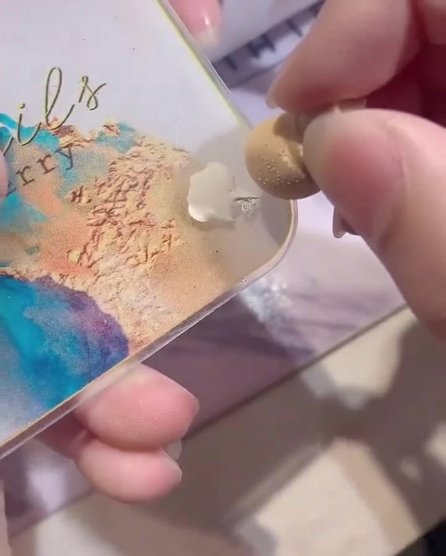 A close-up shot showing a white makeup sponge being loaded with white gel polish from a palette.