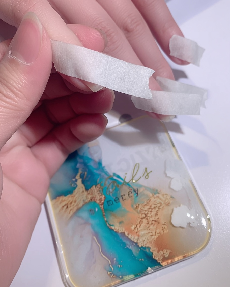A sponge dabbing white gel polish onto the tip of a nail to create an ombre effect.