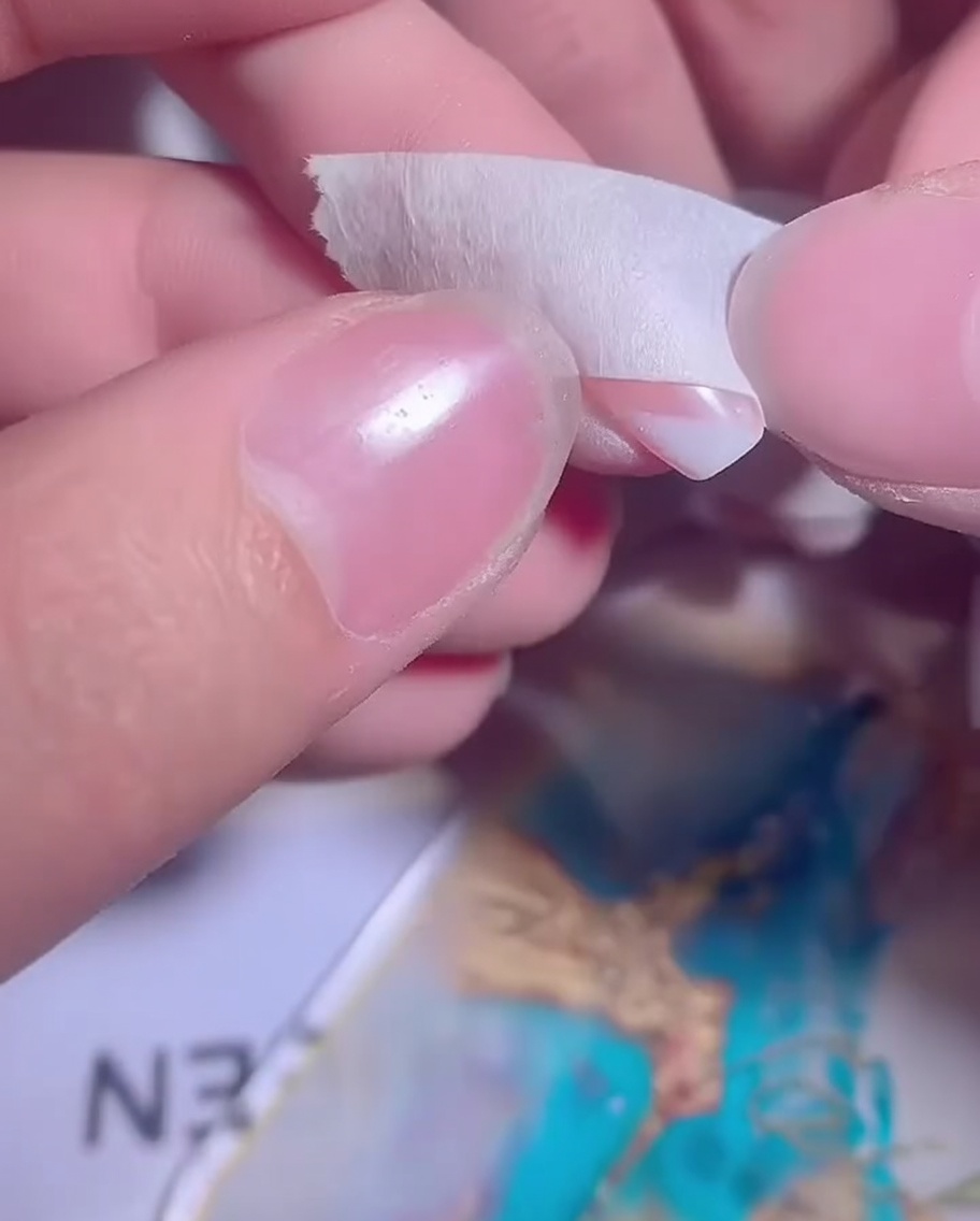 A nail with a partially applied white gel ombre being prepared for a second layer.