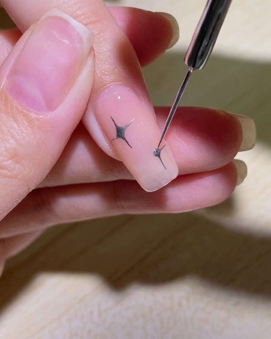 A detailed shot showing small accent lines and a center dot being added to a star design.