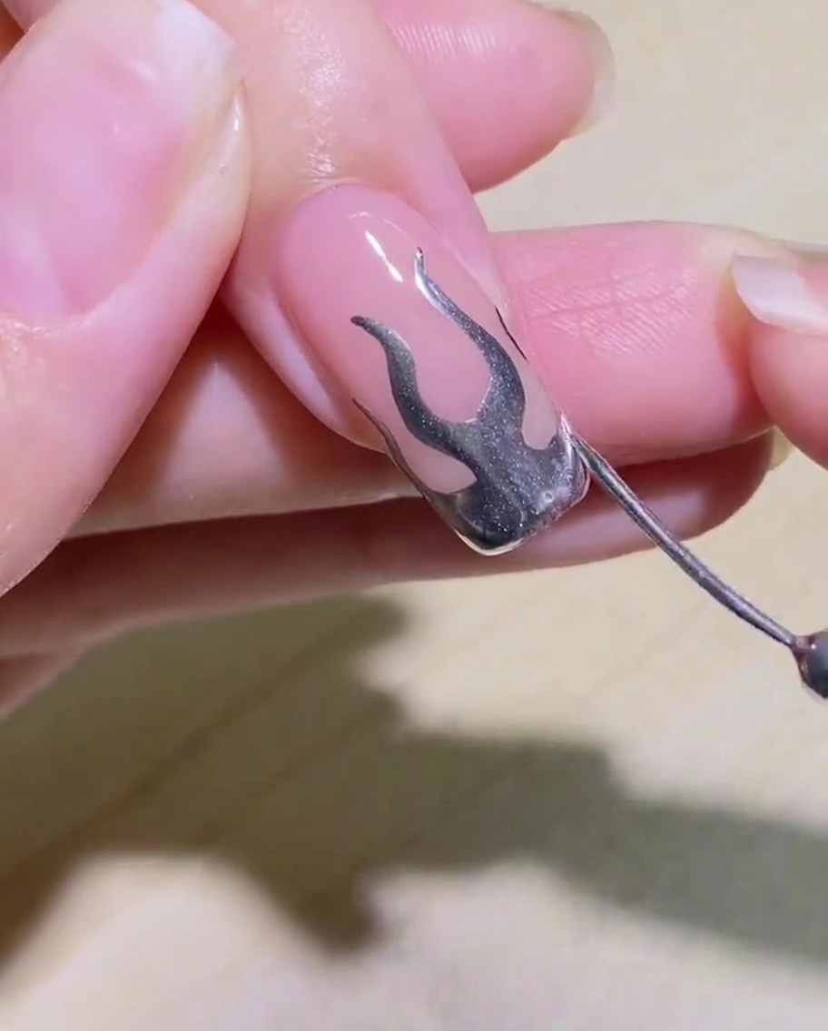 A detailed shot of the finished flame nail design before it is placed under the lamp to cure.