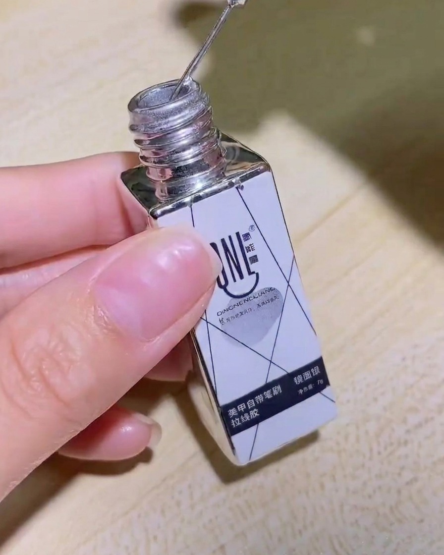 A hand holding the bottle of silver mirror liner gel, showing the product label clearly.