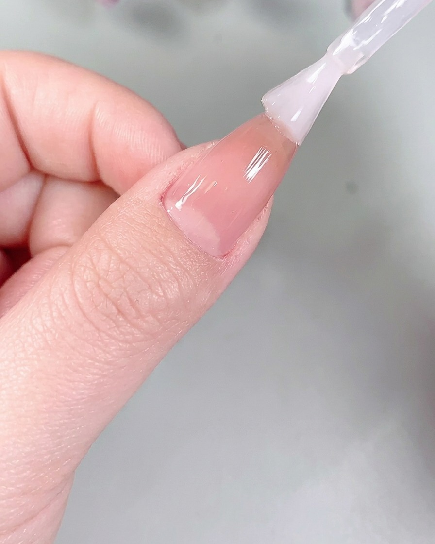 Fingernails placed inside a professional UV/LED nail lamp for curing.