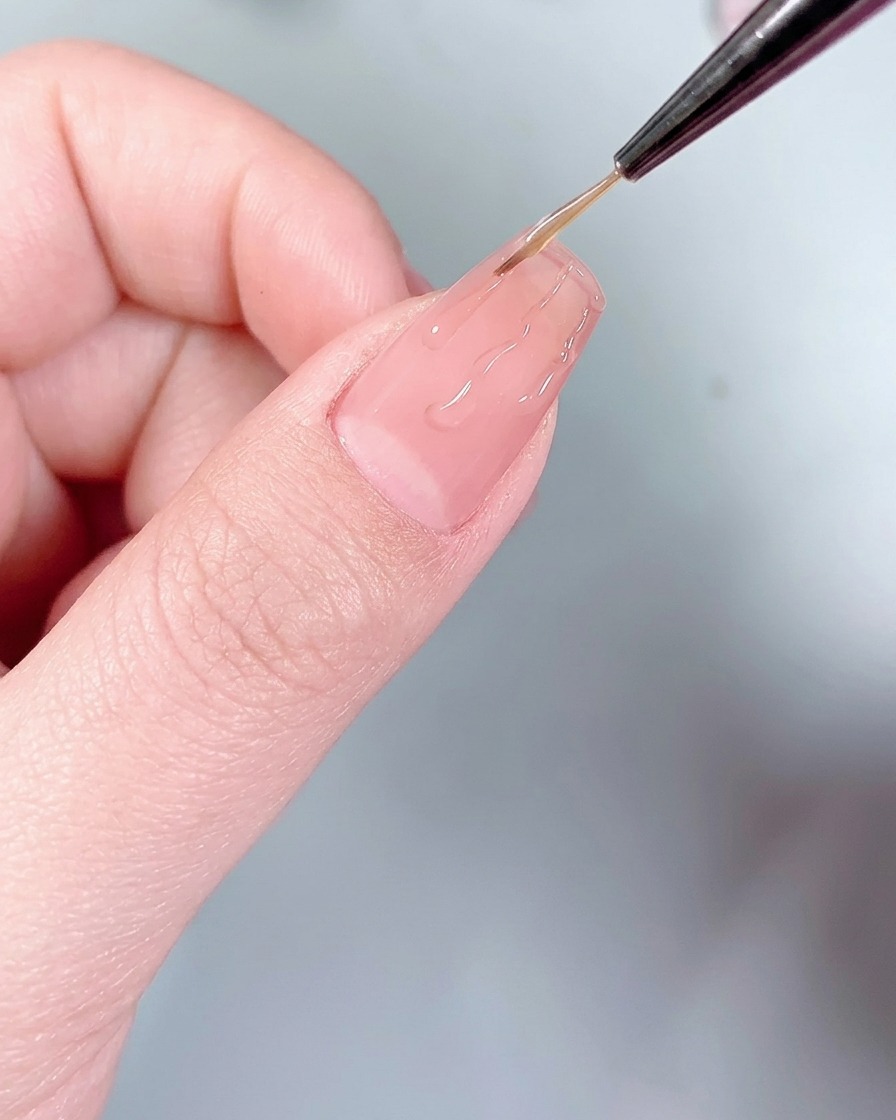 A silicone applicator pressing silver chrome powder onto the flame-shaped glue lines on the nail.