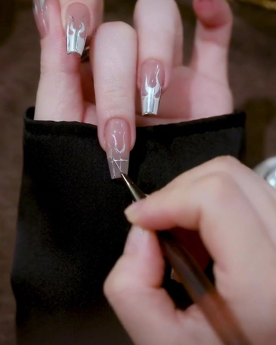 A close-up of a nail showing triangular silver gel shapes drawn on either side of the central U-shapes.