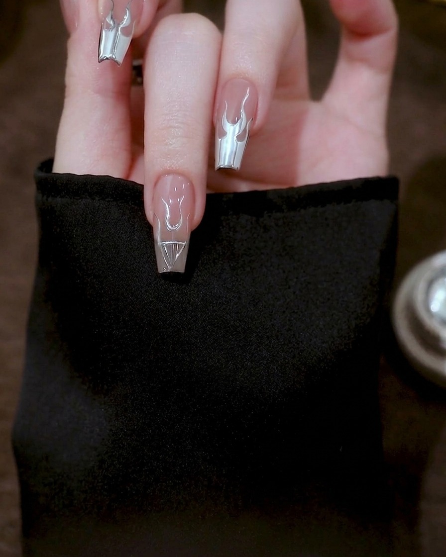 A close-up showing long, curved silver gel lines extending from the flame base down to the edge of the nail.