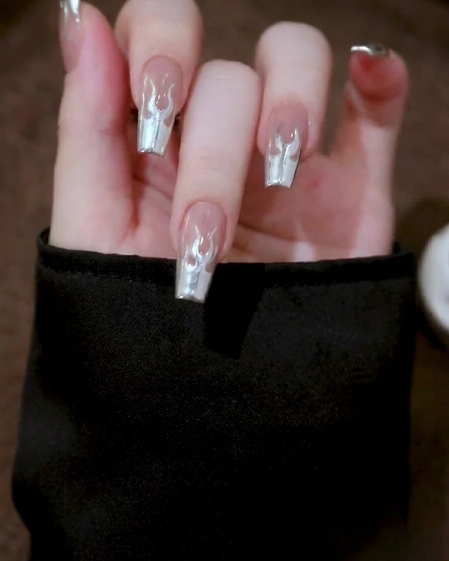 A close-up of a hand placed inside a professional nail lamp, with the metallic gel design undergoing the curing process.