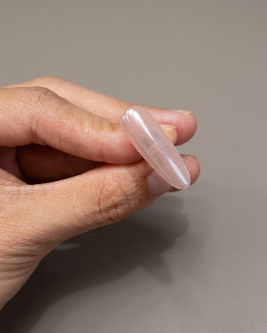 A brush applying a clear, protective layer of gel over a mirror-finished chrome nail.