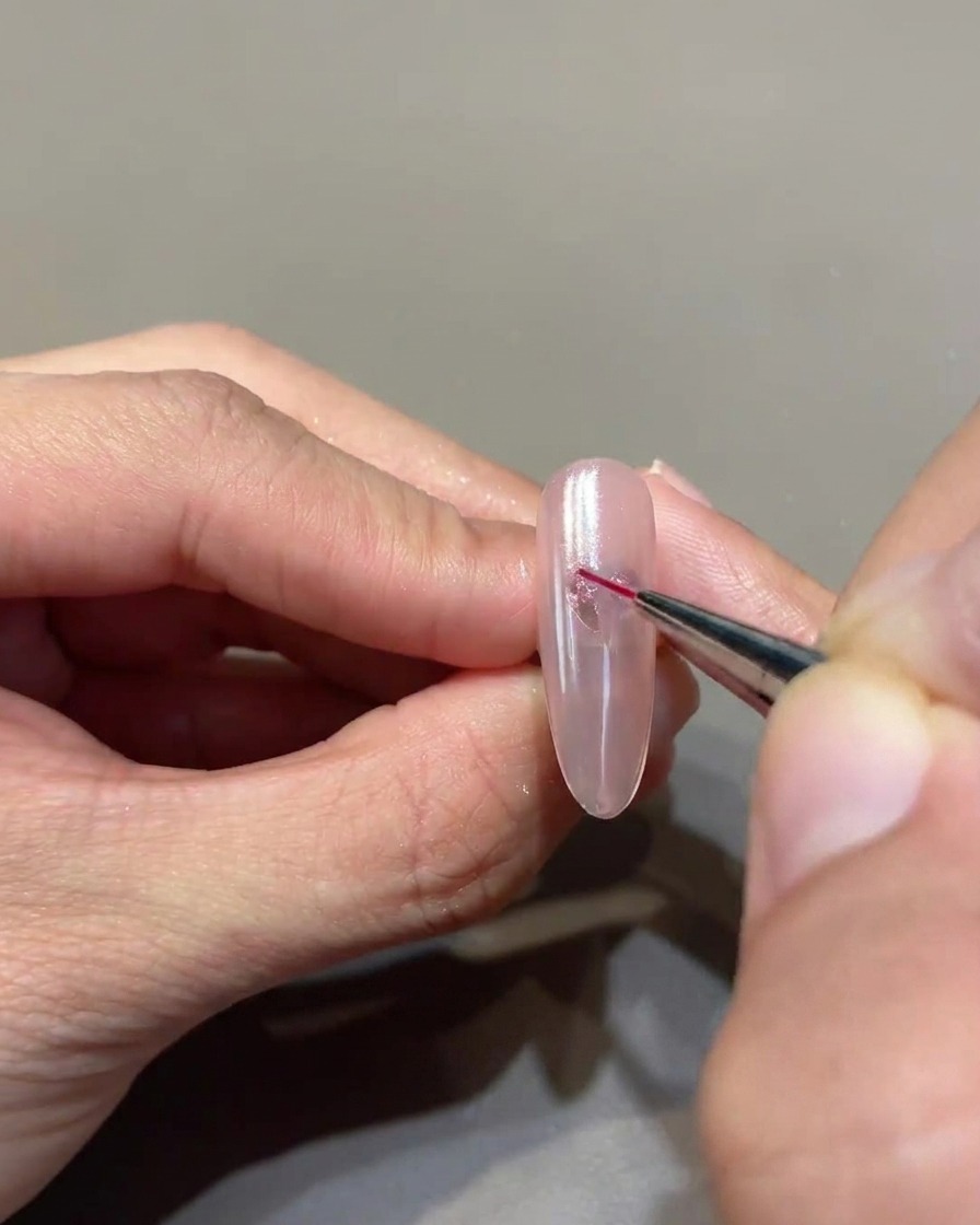 A fine-tipped liner brush meticulously connecting gel dots to form a crisp, defined heart shape on the nail.