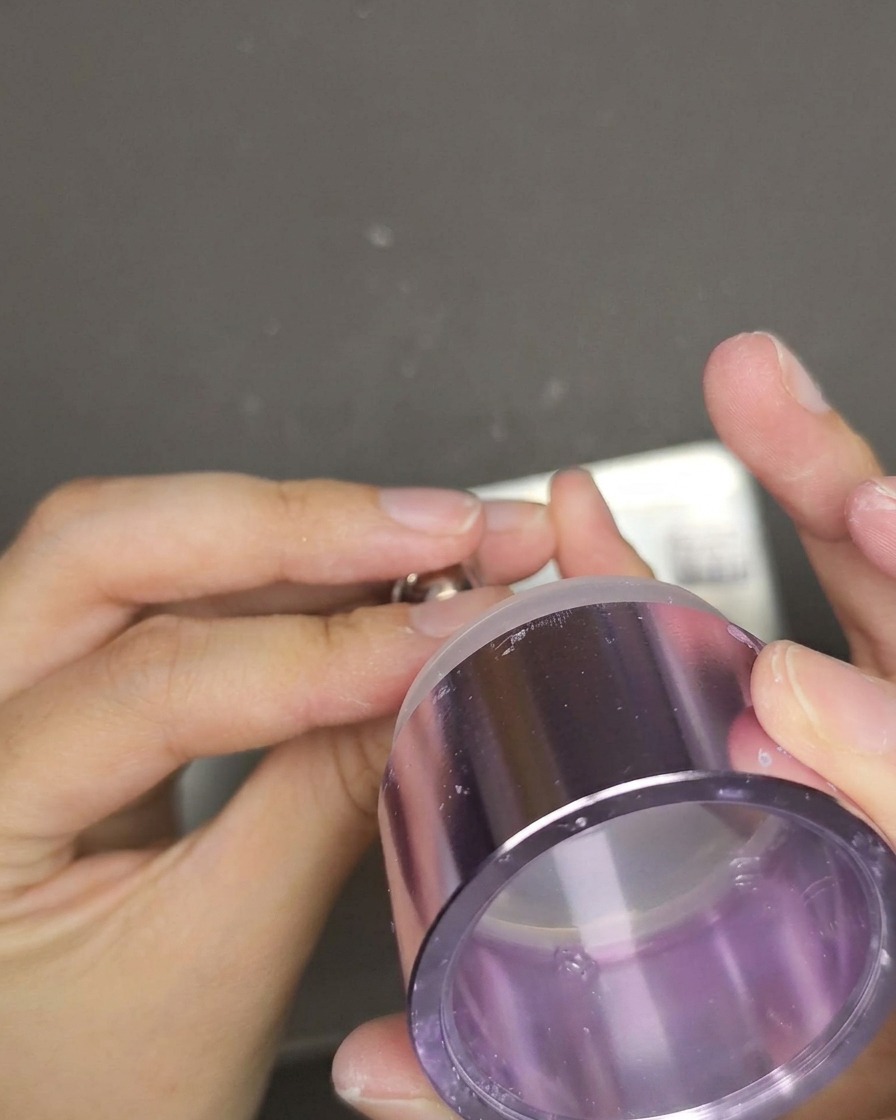 A clear jelly stamper being pressed down onto a red cat eye nail to transfer the white English text design.