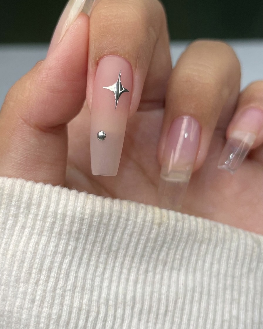 A fine liner brush drawing thin silver lines in a star pattern on a nail.