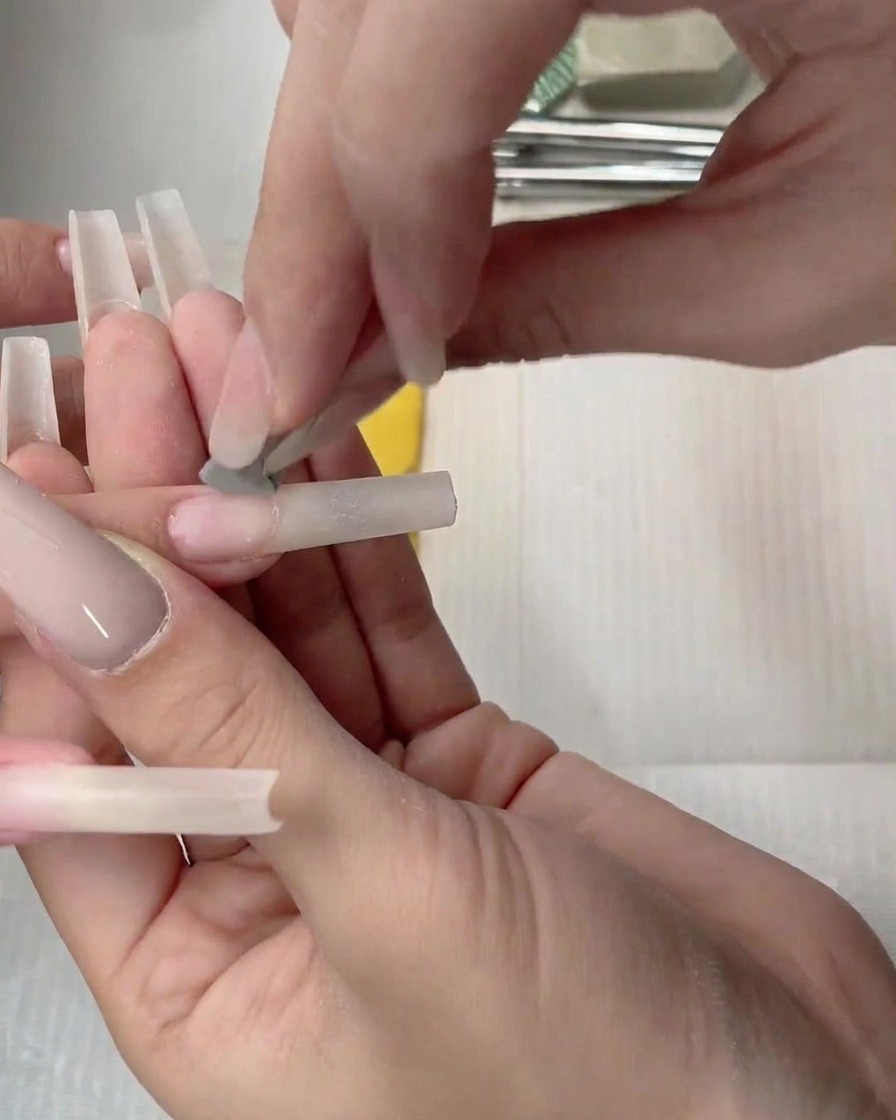 A sponge applicator patting nude gel onto the nail bed to diffuse the color.