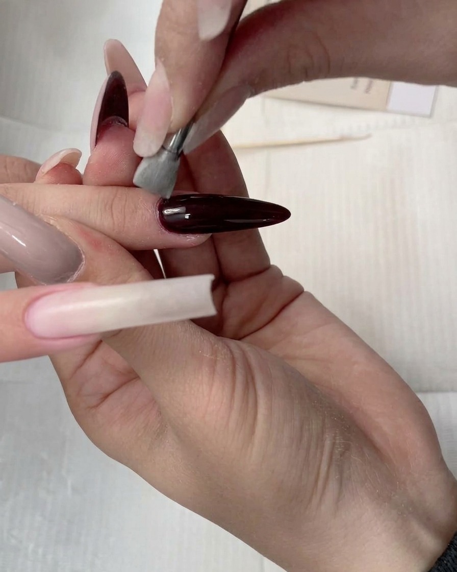 The sponge applicator blending concealer gel down the length of the nail.