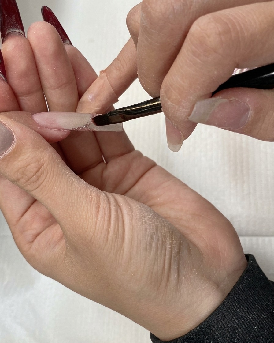 A flat brush dragging glitter downwards to create an ombre effect.