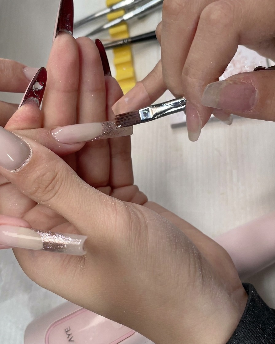 A flat brush performing final blending strokes for a smooth glitter transition.