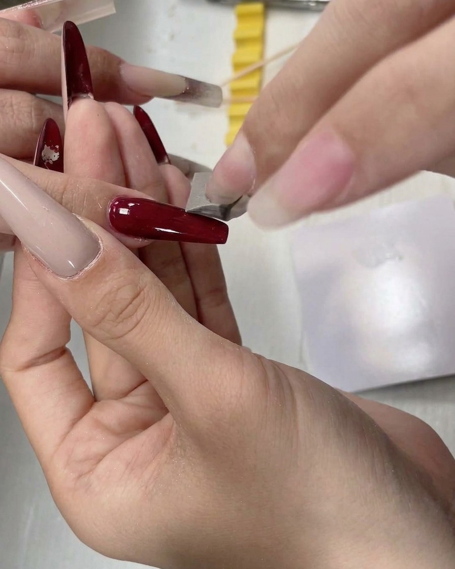 A small sponge tool dabbing white gel onto the free edge of a long nail.
