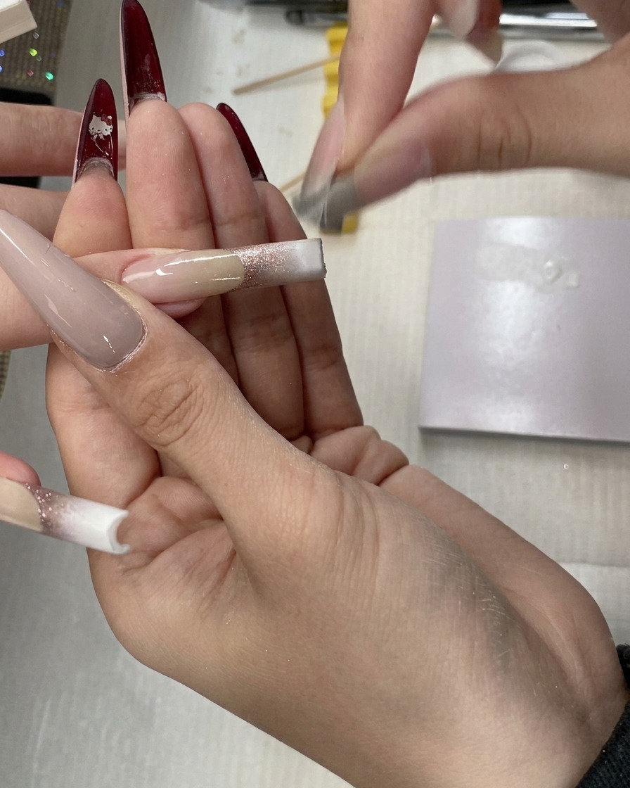 A sponge tool blending white gel upwards on the nail, creating a soft transition for a baby boomer effect.