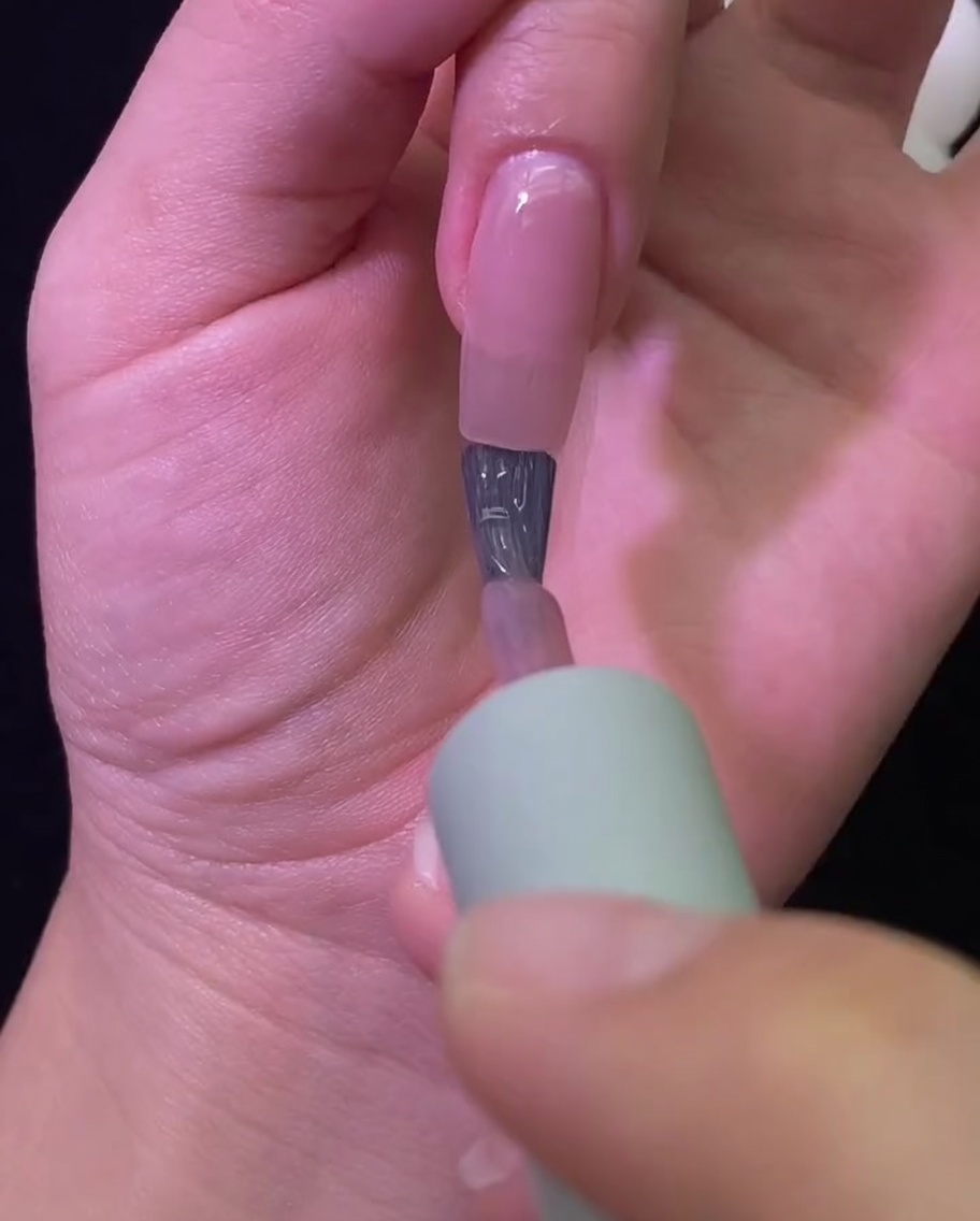 A hand resting inside a professional UV/LED nail lamp with the nail color curing.
