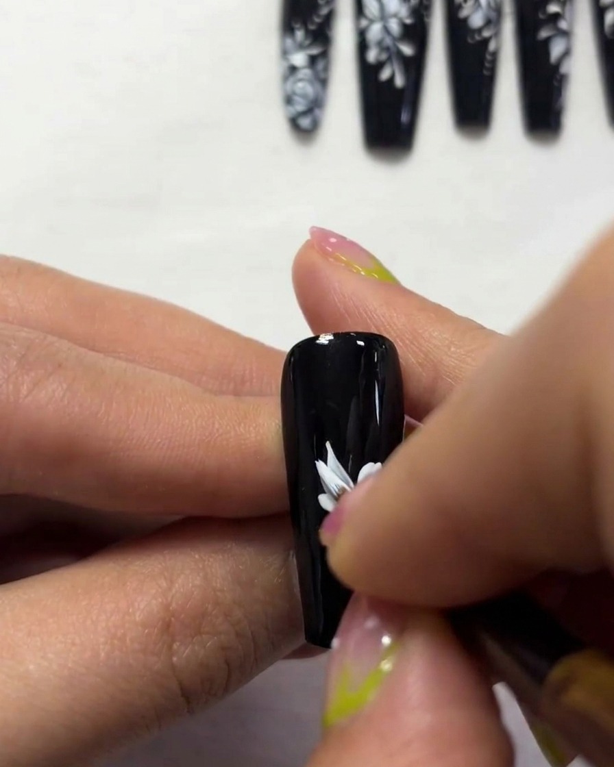 A close-up view showing the detailing of butterfly wing edges with white paint on a black nail.