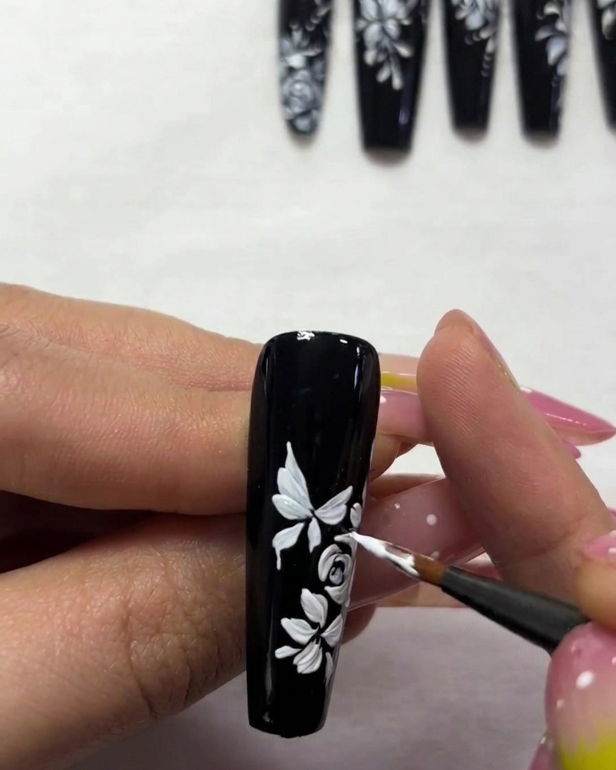 A detailed close-up showing the addition of fine white antennae and small dots surrounding the butterfly nail art.