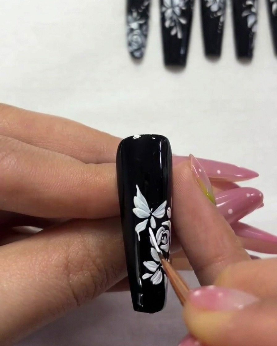 A close-up of a nail showing a smaller, secondary butterfly being painted toward the top edge.