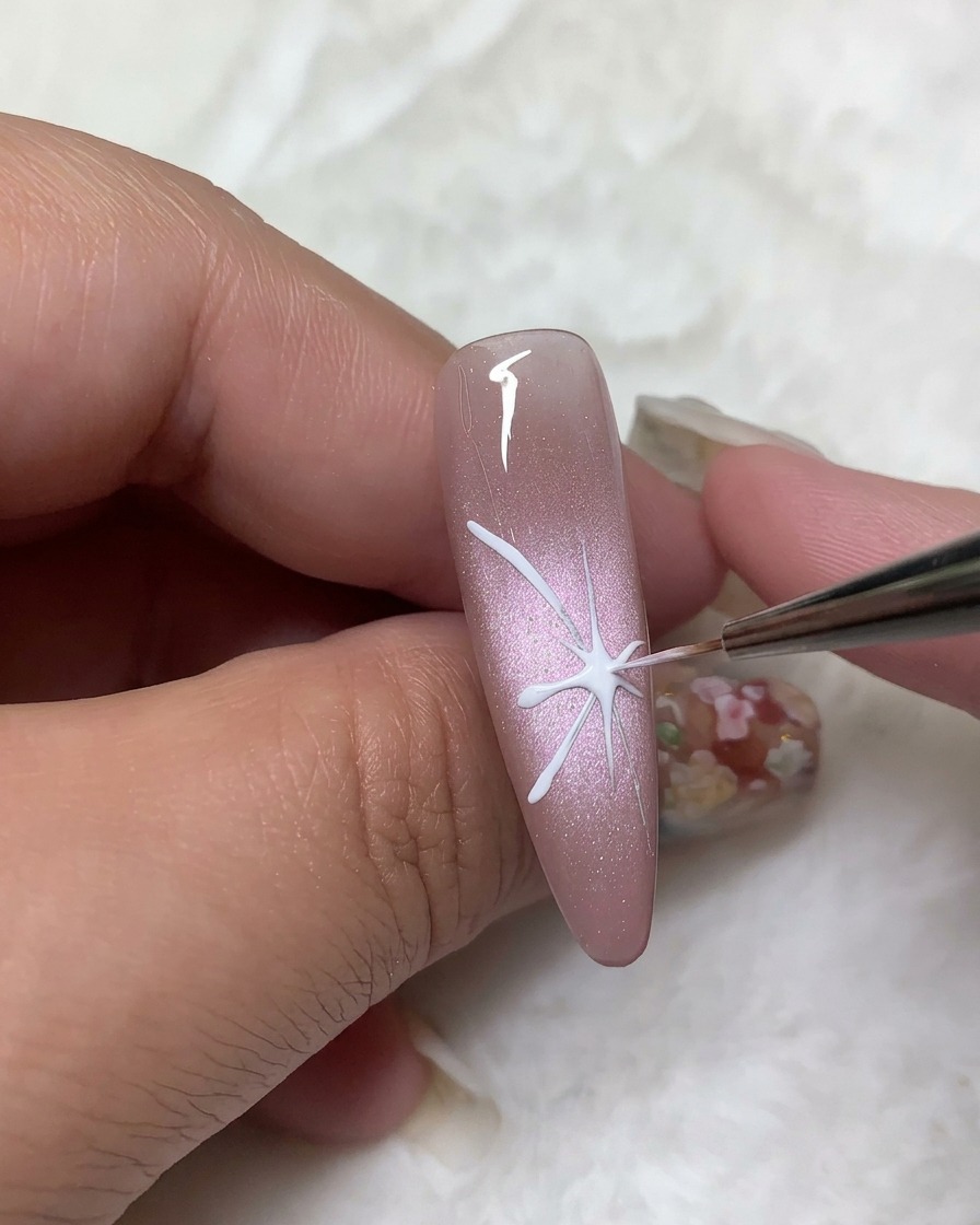 A detail brush filling in the upper butterfly wing outlines with opaque white gel polish.
