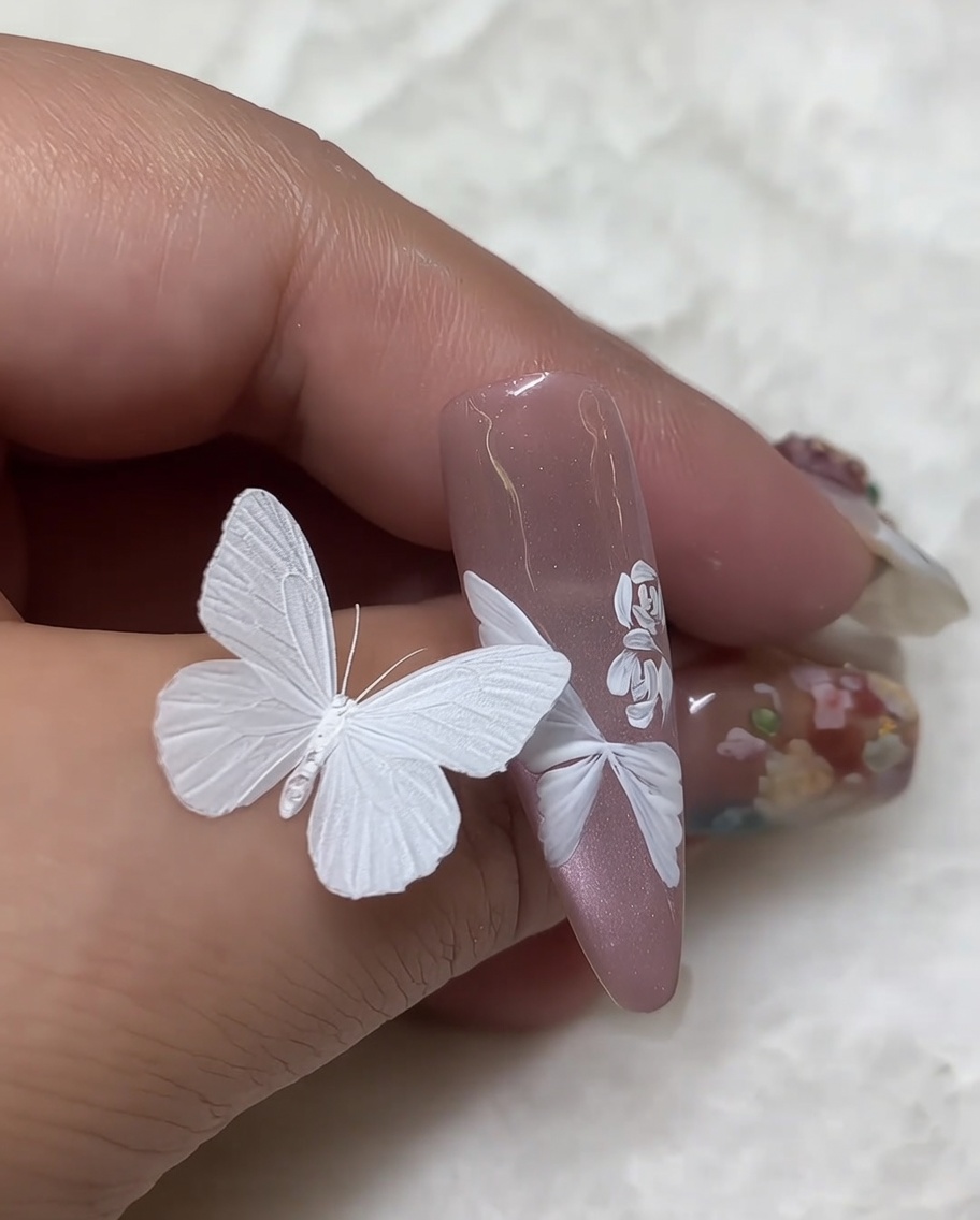 Macro detail shot of a finished white rose nail art design with the center deepened using small, dense white paint strokes.