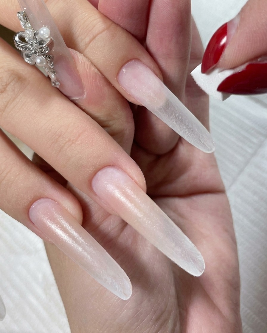 A hand resting inside an LED curing lamp with the nude gel polish currently setting.