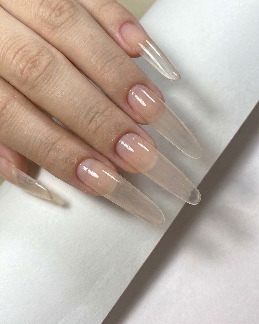 A second layer of nude-toned gel being applied to the nail surface to deepen the color.