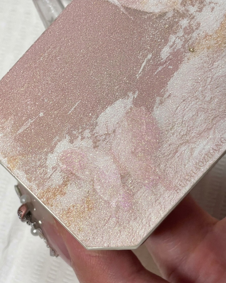 A close-up view of a thin liner brush applying sparkling champagne-colored glitter gel to the free edge of a natural-looking nail.