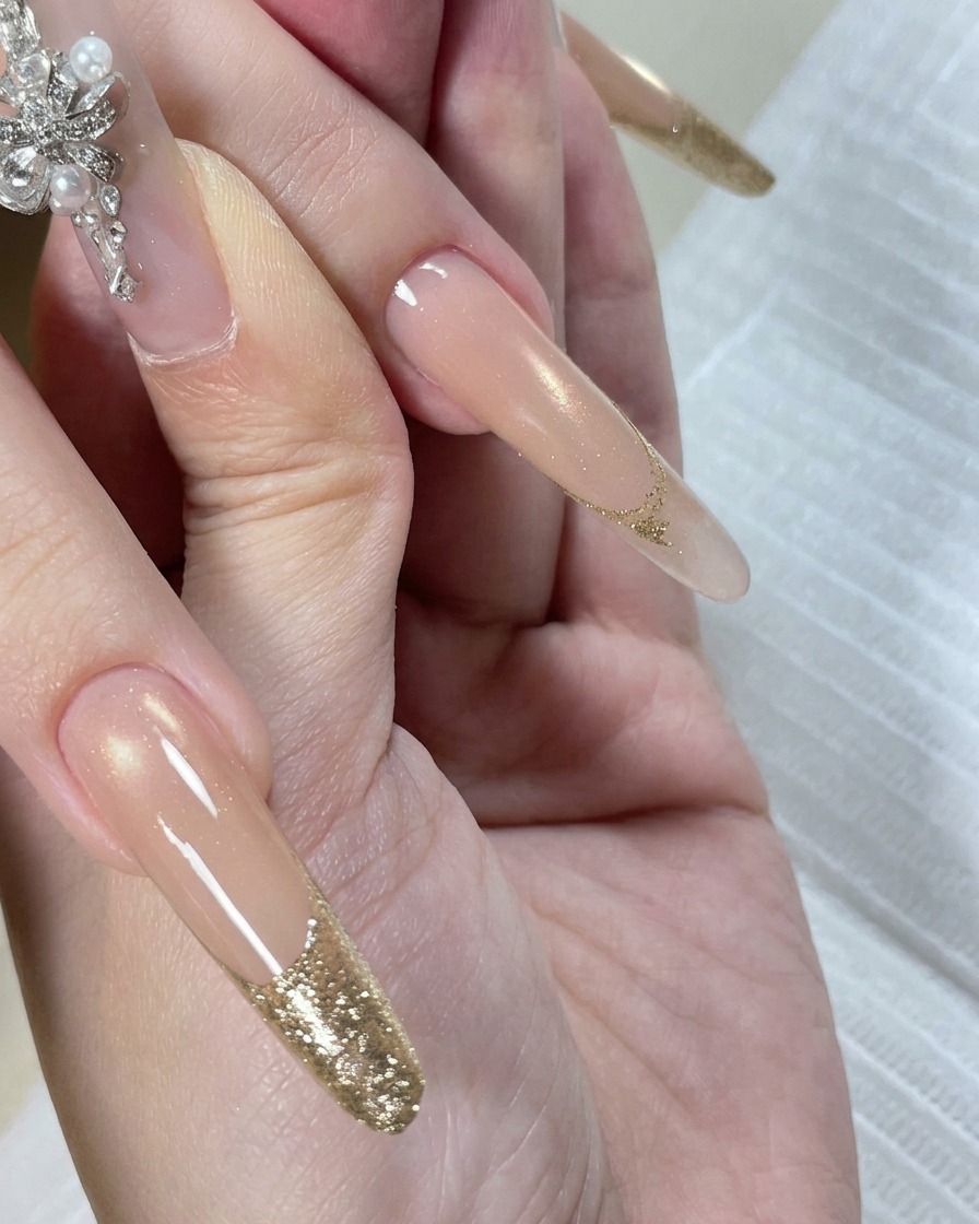 A hand resting inside an LED nail lamp with the tips of the nails illuminated by the light during the curing process.
