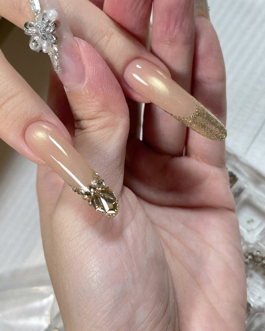 A precision applicator tool placing a small bead of clear adhesive gel onto the surface of a nail at the base of the glitter tip.